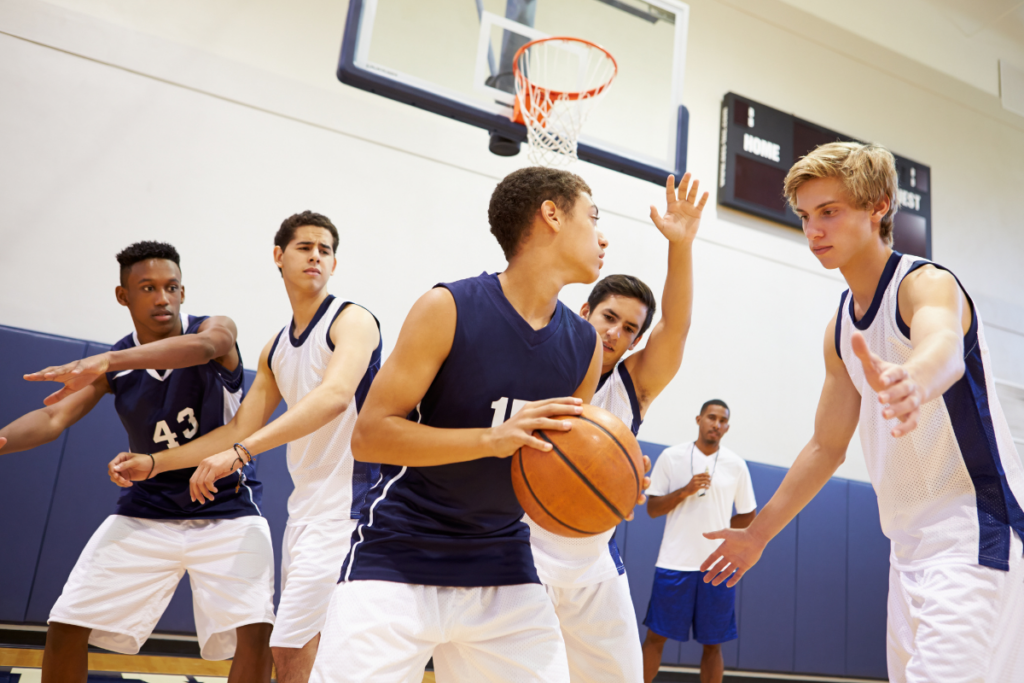Alunos de ensino médio High School jogando basquete na quadra escolar.