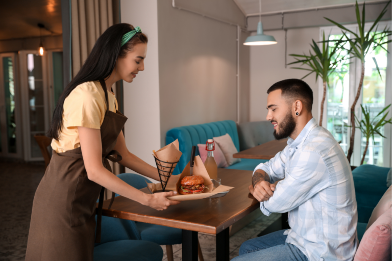 Atendente servindo um cliente em um restaurante na Irlanda, destacando o setor de hospitalidade e turismo, uma área com muitas oportunidades para quem busca fazer um intercâmbio na Irlanda